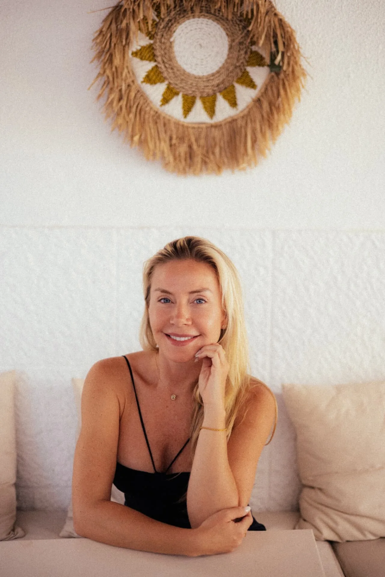 Juliana Gruber, host of Casa Caparica, smiling on a light coloured sofa