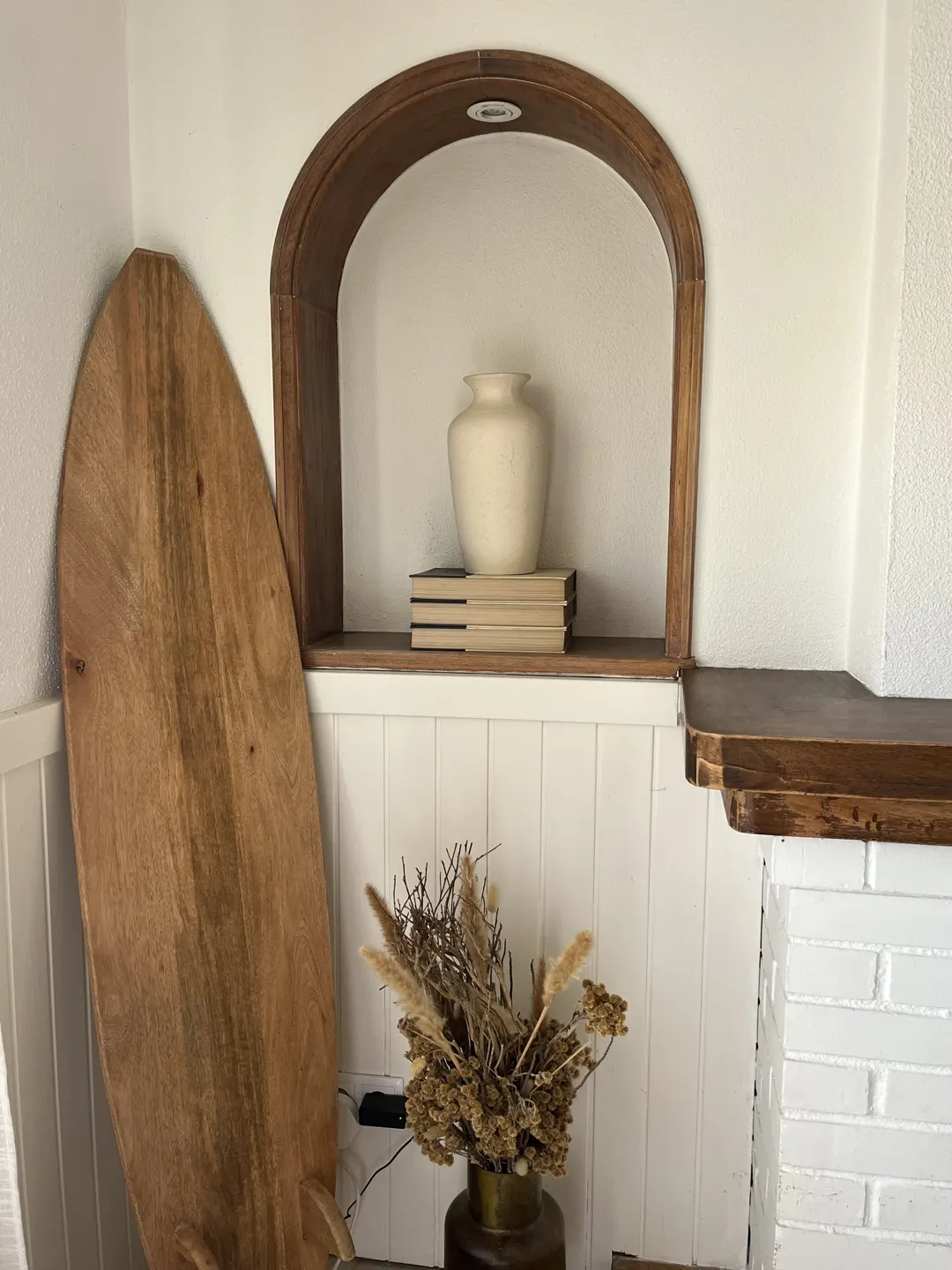 Arched niche with a clay pot, books and a surfboard