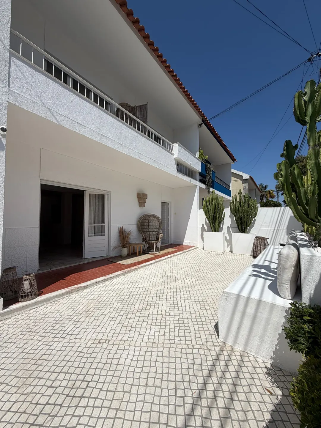 White house facade with a Portuguese-cobble patio and cacti