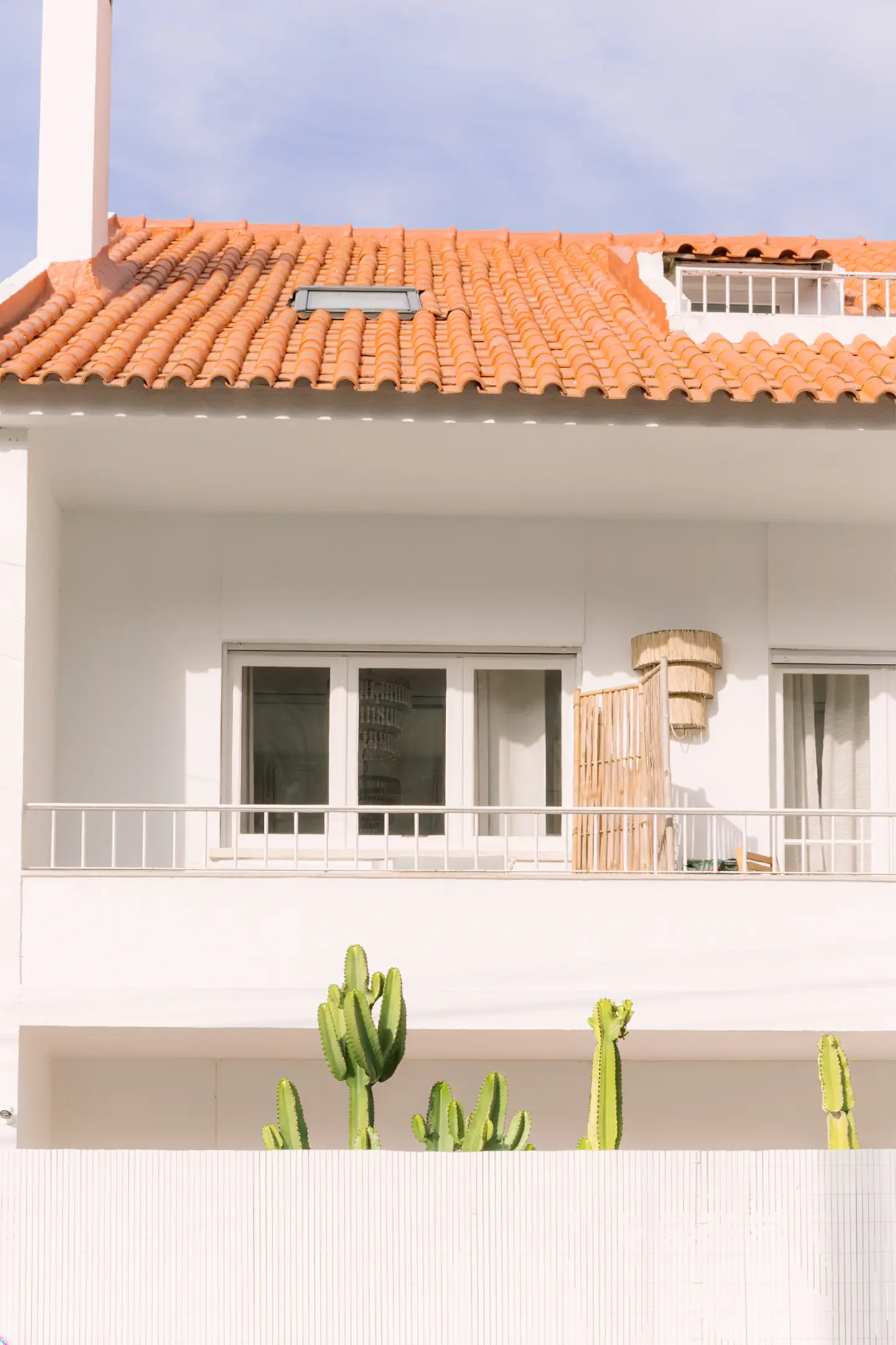 Fachada branca com telhado de telha e cactos