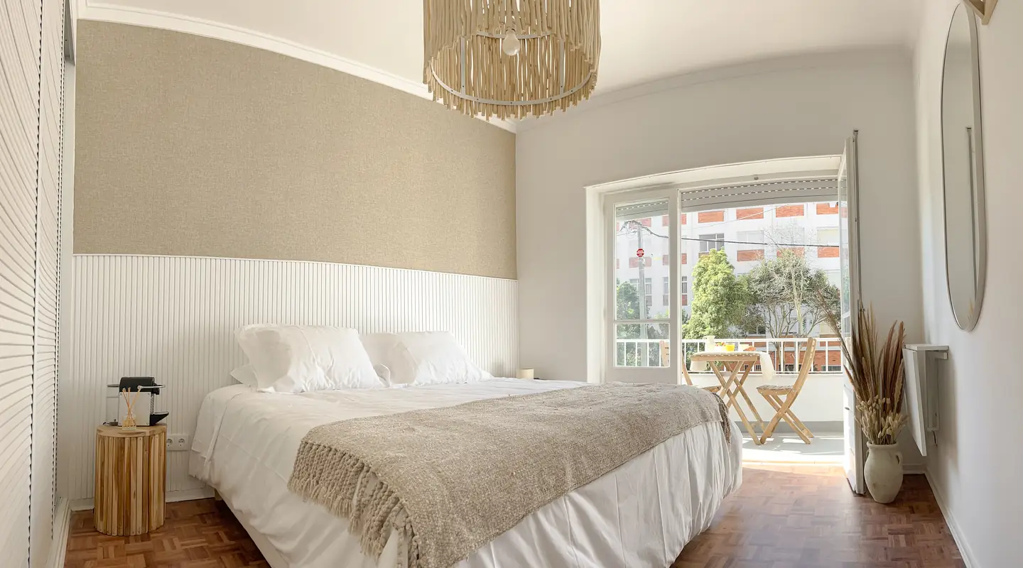 Quarto duplo com cama de casal, cabeceira de madeira e luz natural