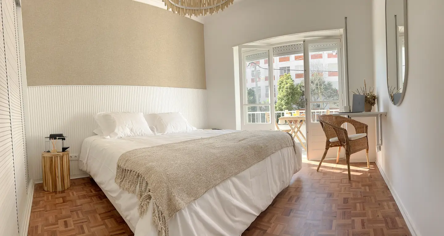 Castelo room with light bedding and a desk by the window