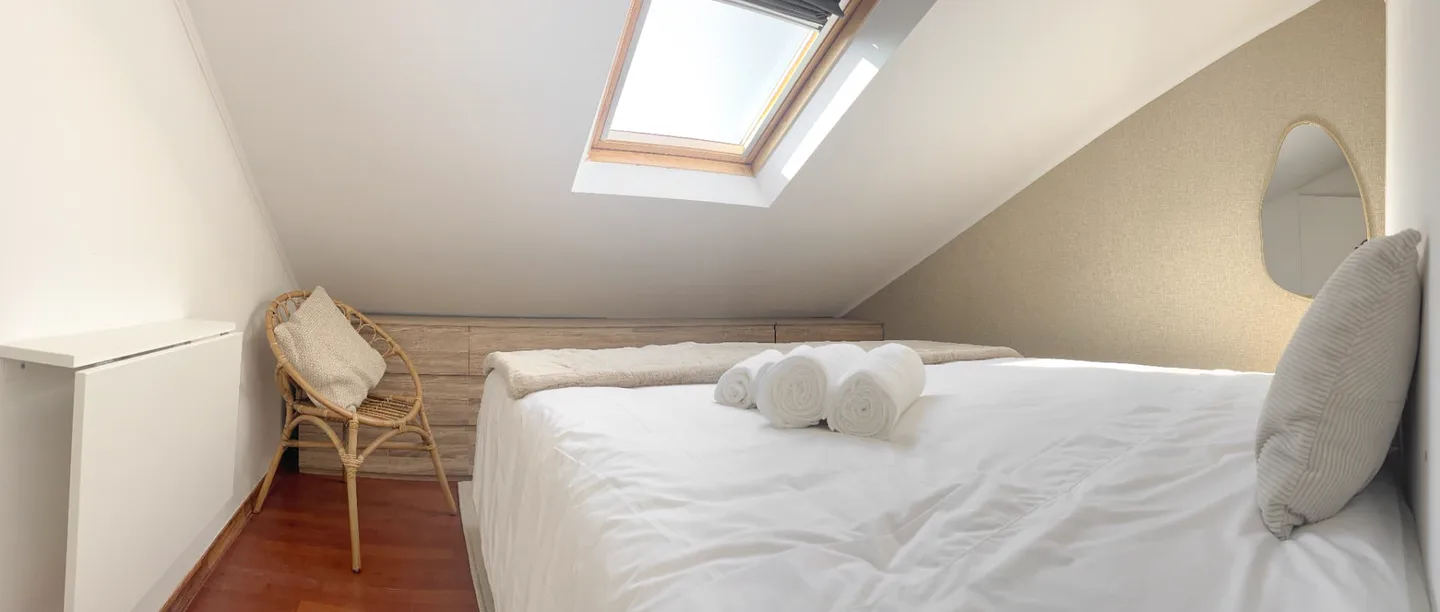 Quarto do piso superior com janela de tecto e madeira à vista