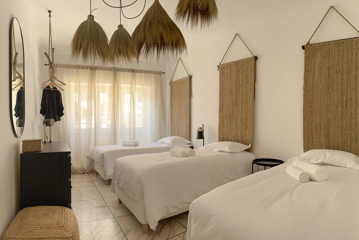 Quarto triplo com camas em linho claro e cabeceiras em fibra natural
