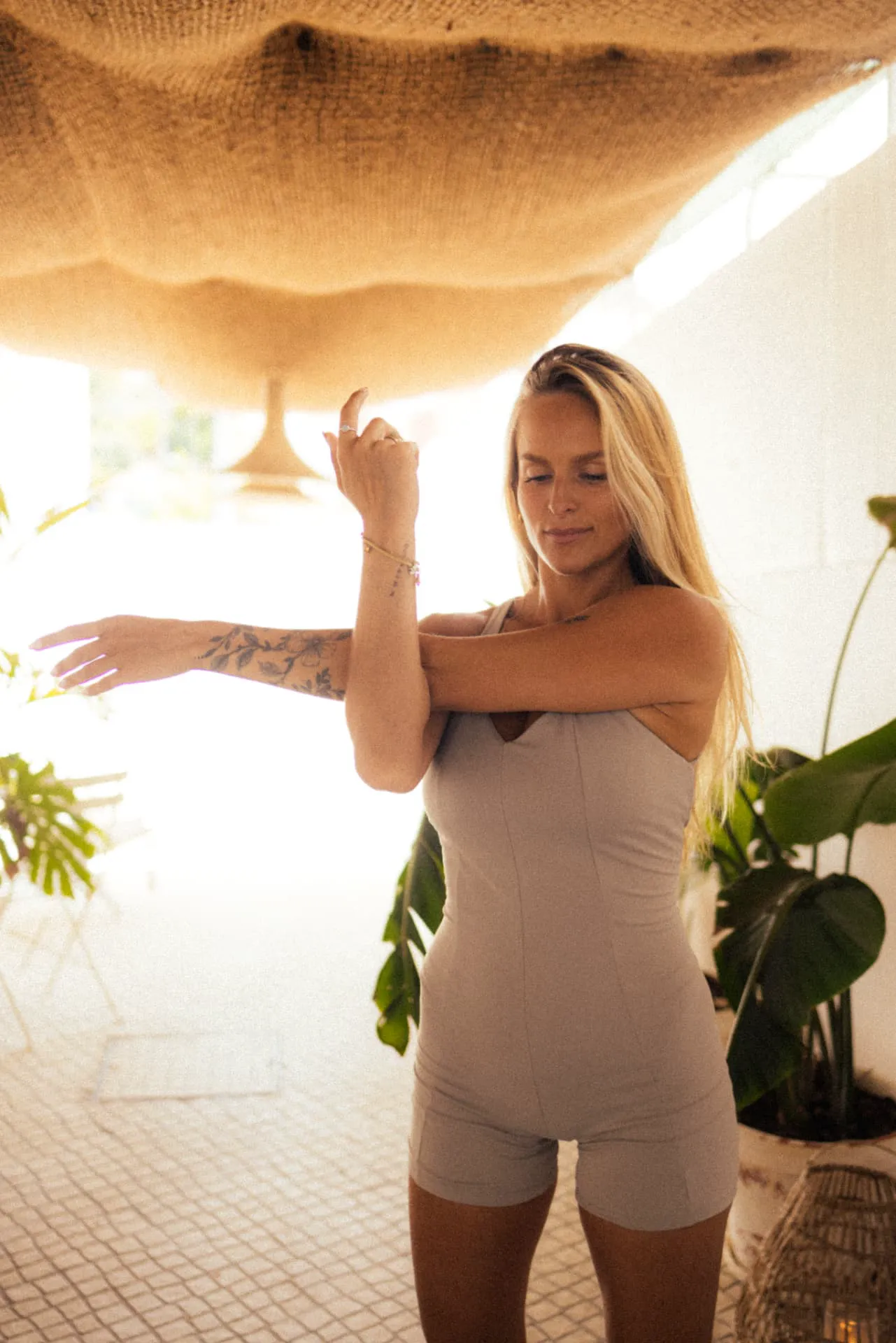 Pilates teacher standing and stretching an arm on the porch, backlit